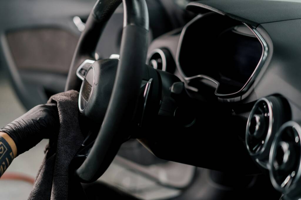Worker cleans steering wheel professional brush and clout of microfiber detailing